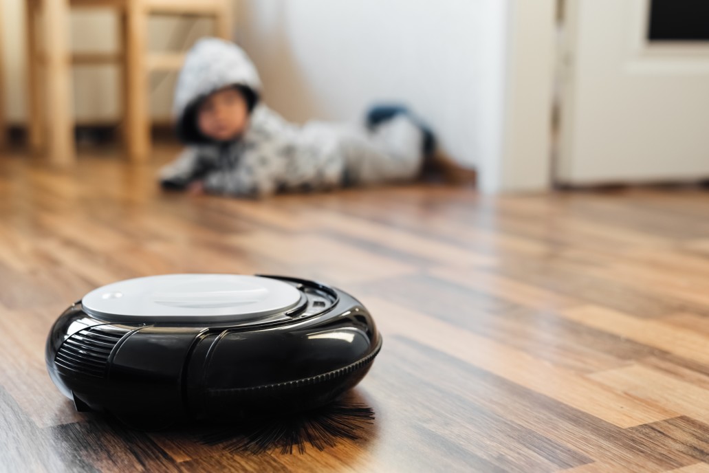 robotic-vacuum-cleaner-on-laminate-floor-with-baby-boy-on-background_t20_9kbyjy